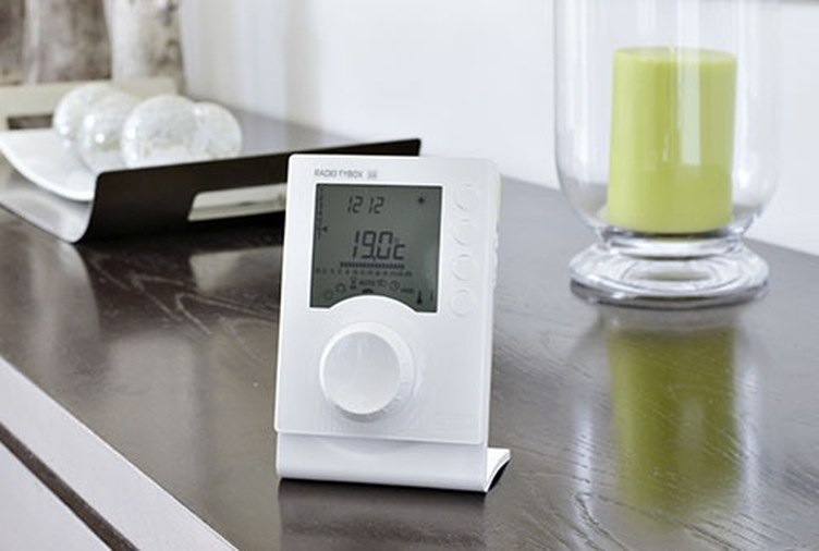 Thermostat d'ambiance digital avec molette de réglage posé sur un meuble